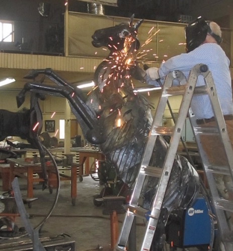 Image of Jim Dolan in his studio welding "Rocking Free" sculpture